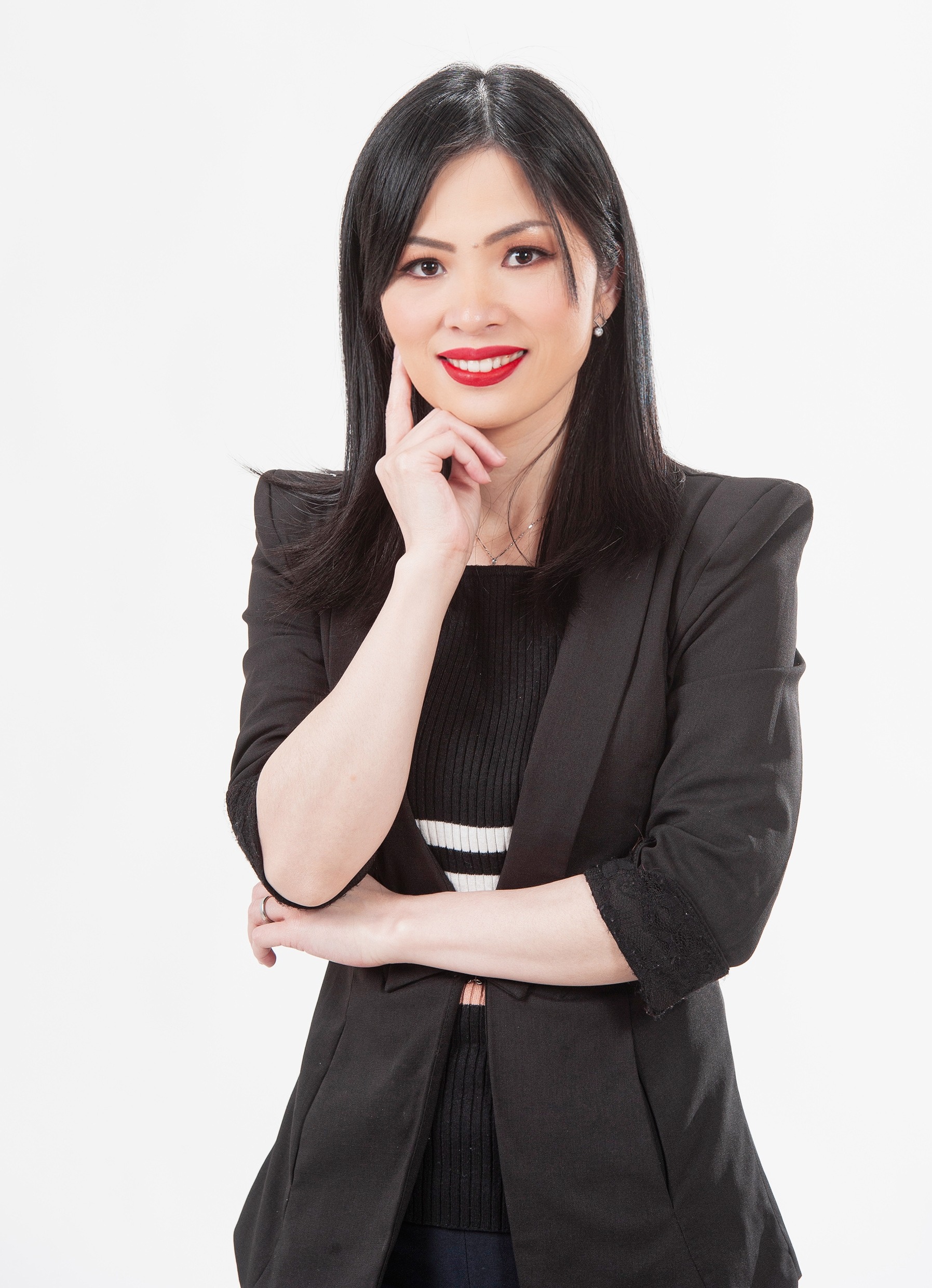 Smiling woman with black long hair, wearing a red short-sleeved dress and a mini mic clipped to her collar, against a blue background.